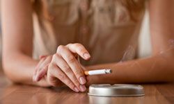 Woman's hand with cigarette and ashtray