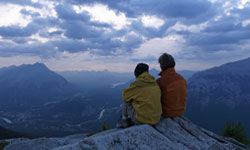 Two people in a loving relationship atop a mountain.