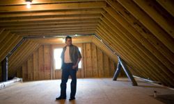 A man standing in a newly insulated attic.&nbsp;
