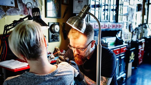 man tattooing woman