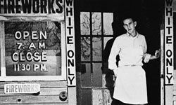 A young man stands in the doorway of a store marked "White Only, " circa 1950., in the U.S. South.”border=