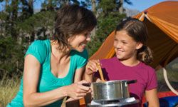 mother and daughter sharing campfire meal