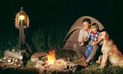 father, son and dog by campfire