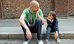 father and son sitting on a curb