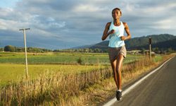 Running down a country road, this runner has a long training run to increase her endurance.