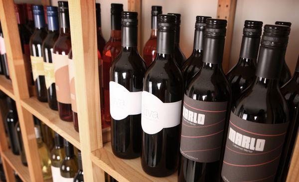 Wine bottles are on a shelf.