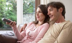 woman and man lounging in living room with TV remote