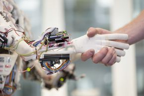 2013年6月21日，由苏黎世大学人工智能实验室开发的人形机器人ROBOY与人类机器人握手。通过使用3d打印技术，ROBOY只用了9个月就开发出来了。＂border=