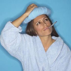 woman wearing bath robe with thermometer in her mouth