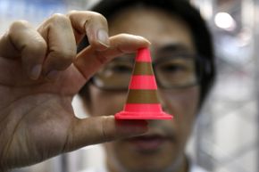 A staff member of Nihon Binary shows an Acrylonitrile butadiene styrene pylon (similar to a plastic traffic cone) which was printed by the 3-D printer MakerBot Replicator 2X during the International Robot Exhibition 2013 in Tokyo.