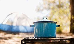 Camping outdoors and cooking delicious food in a pan.