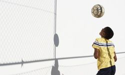 boy bouncing soccer ball against wall