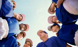 young baseball players huddle up with coach