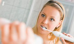 woman using electric toothbrush