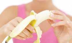 Banana being peeled in foreground by woman in background