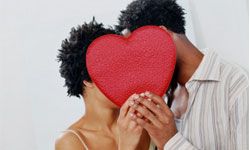 man kissing woman behind Valentine's heart