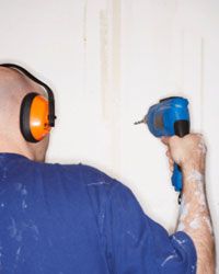 man using drill and wearing earplugs