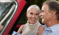 retired couple driving convertible