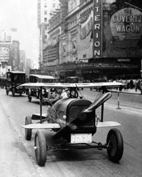 A car with wings and a propeller protruding from the radiator grille drives through Times Square, New York. This car was the invention of A.H. Russell of Nutley, New Jersey.