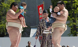 Sumo students with babes in arms gear up to make them cry.