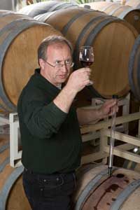 A professional winemaker uses a wine thief to sample a glass straight from the cask.