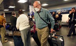 波士顿洛根国际机场的一名旅客从波多黎各飞抵机场后，在滚动行李时戴上了口罩，以预防猪流感。＂width=