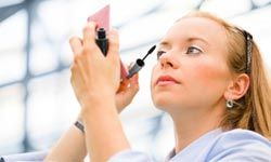 Businesswoman applying mascara