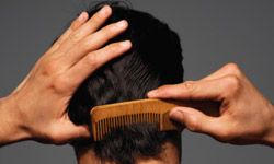 Dark-haired man combing back of hair