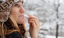 Woman applying lip balm in wintry weather