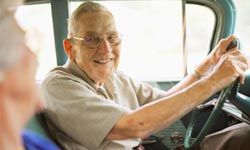 caucasian male senior citizen smiling in the driver's seat of a truck