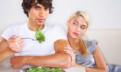 Woman watches man eat spinach