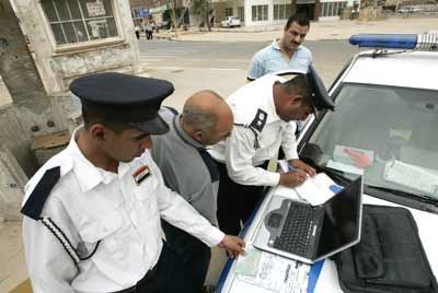 Iraqi police officers use a laptop to fine drivers caught driving without seatbelts in Baghdad.